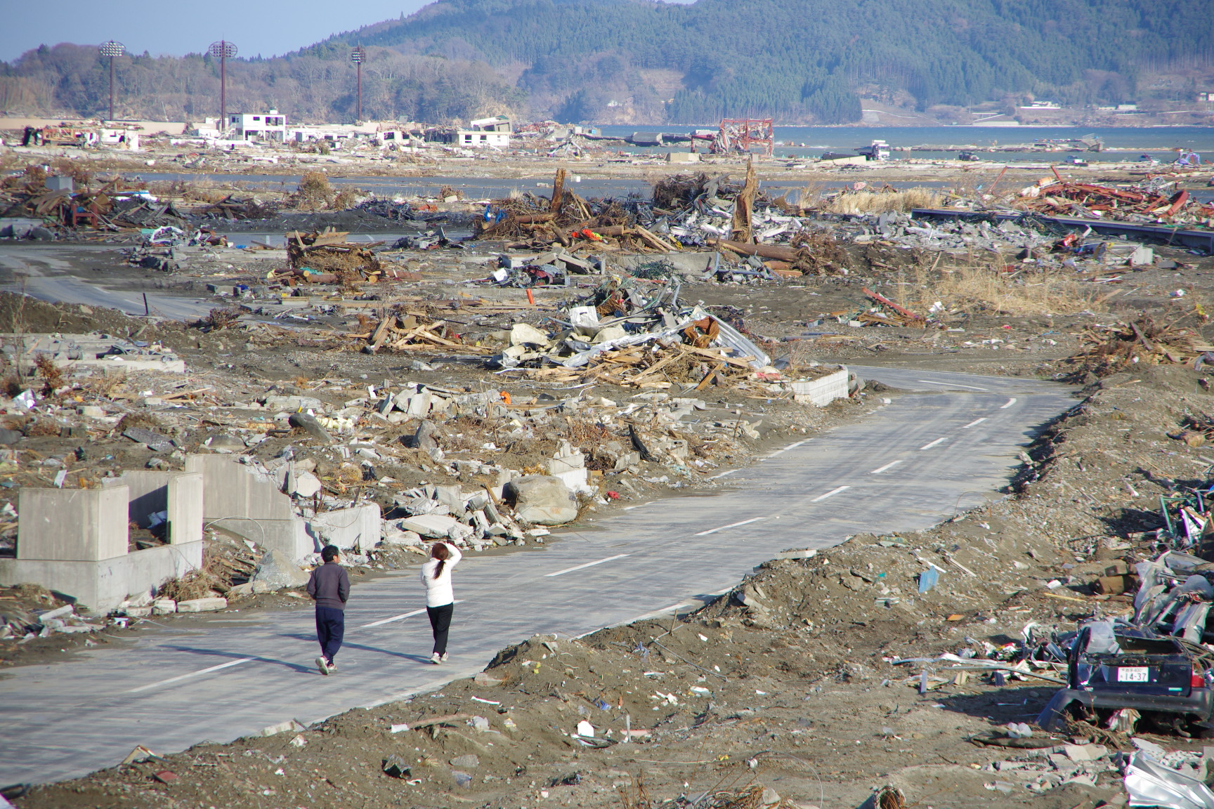 東日本大震災、津波によって一変した町と奇跡的に残った道路を歩く人